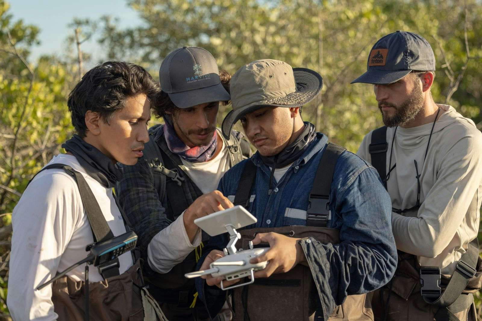 Men looking at drone surveilling a forest.